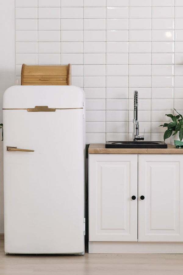 white refrigerator on a white and light brown themed kitchen
